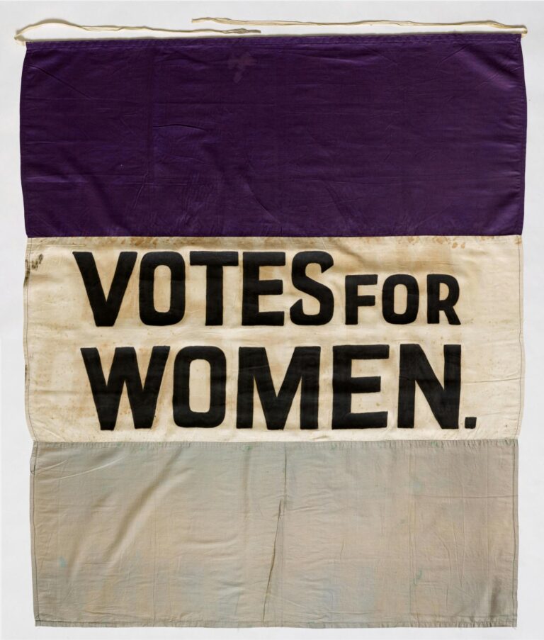 Celebrating Political Women - image of a purple, white, and grey Suffragette flag with the Votes for Women slogan