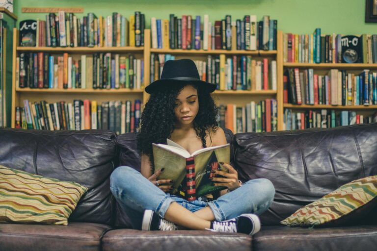 Image of a woman sitting cross-legged on a leather sofa reading for pleasure